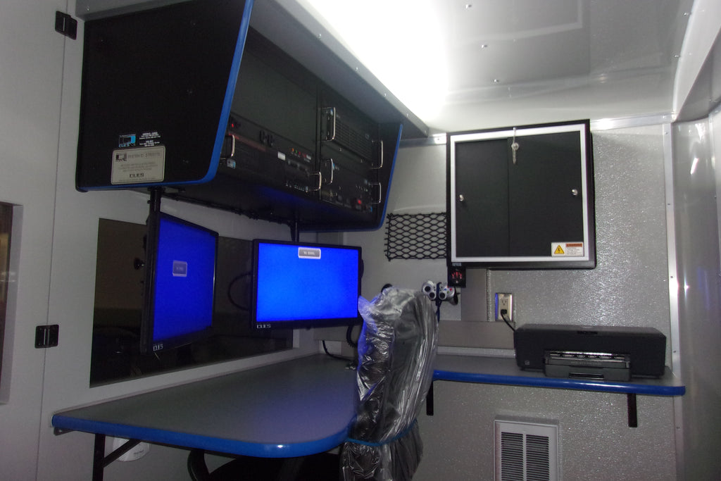 CUES trailer-mounted inspection system control room with two monitors, equipment rack, desk and printer