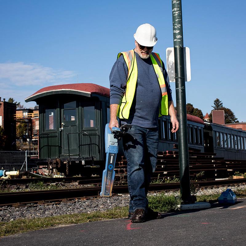 CUES Accupoint locator carried by a worker beside railroad tracks